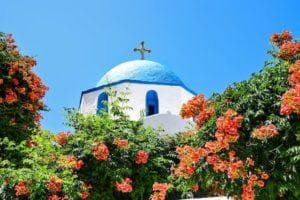 blue and white church with red flowers around it