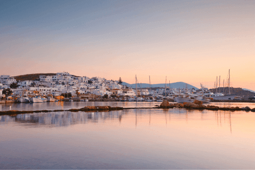 white bulduings front of the sea while the sun goes down in Paros