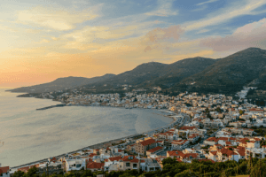 Goddess in the town of Samos with many houses next to the sea and the sunset creating orange hues in the sky