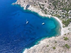 blue beach with two white boats on the island of ikaria