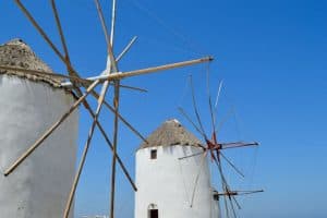 two white windmills set against a blue sky on the greek island of mykonos