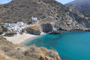 sandy beach with white buildings among wild rocks with minimal vegetation