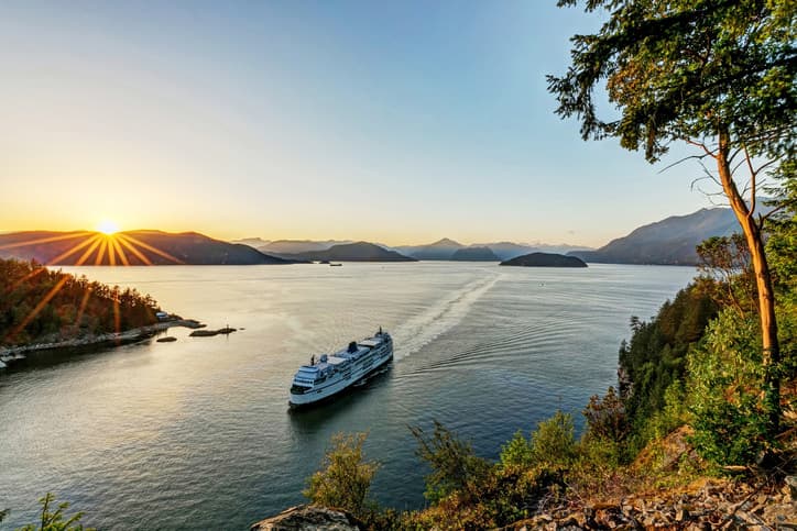 Ferry sailing across a wide body of water at sunset