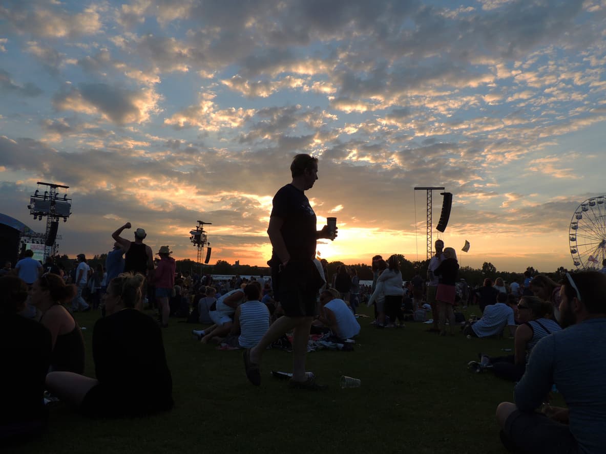 Un homme savoure sa boisson devant un coucher de soleil splendide à un festival.