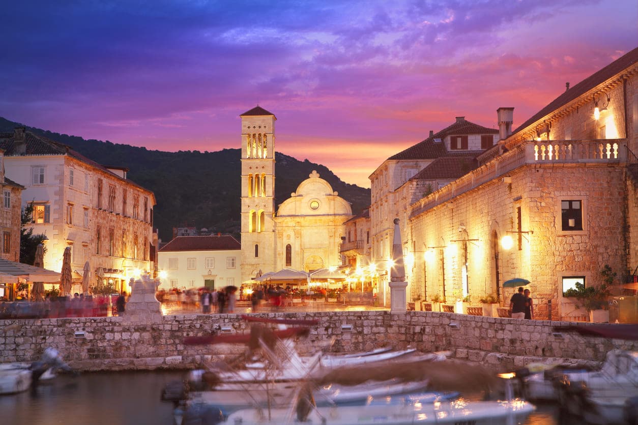 Trg Svetog Stjepana u gradu Hvaru na otoku Hvaru s upaljenim svjetlima u sumrak.