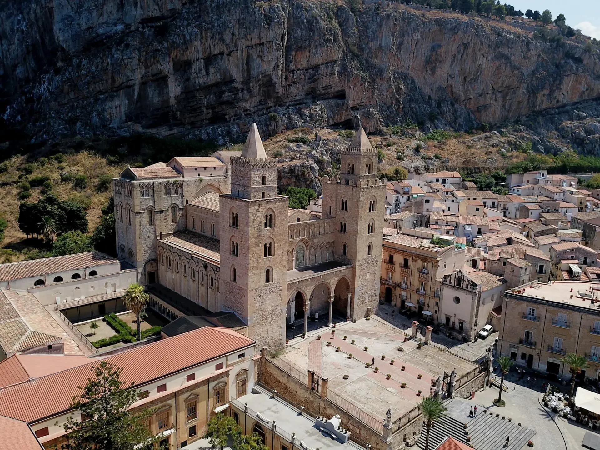 Une grande cathédrale devant une falaise, donnant sur un petit village côtier.