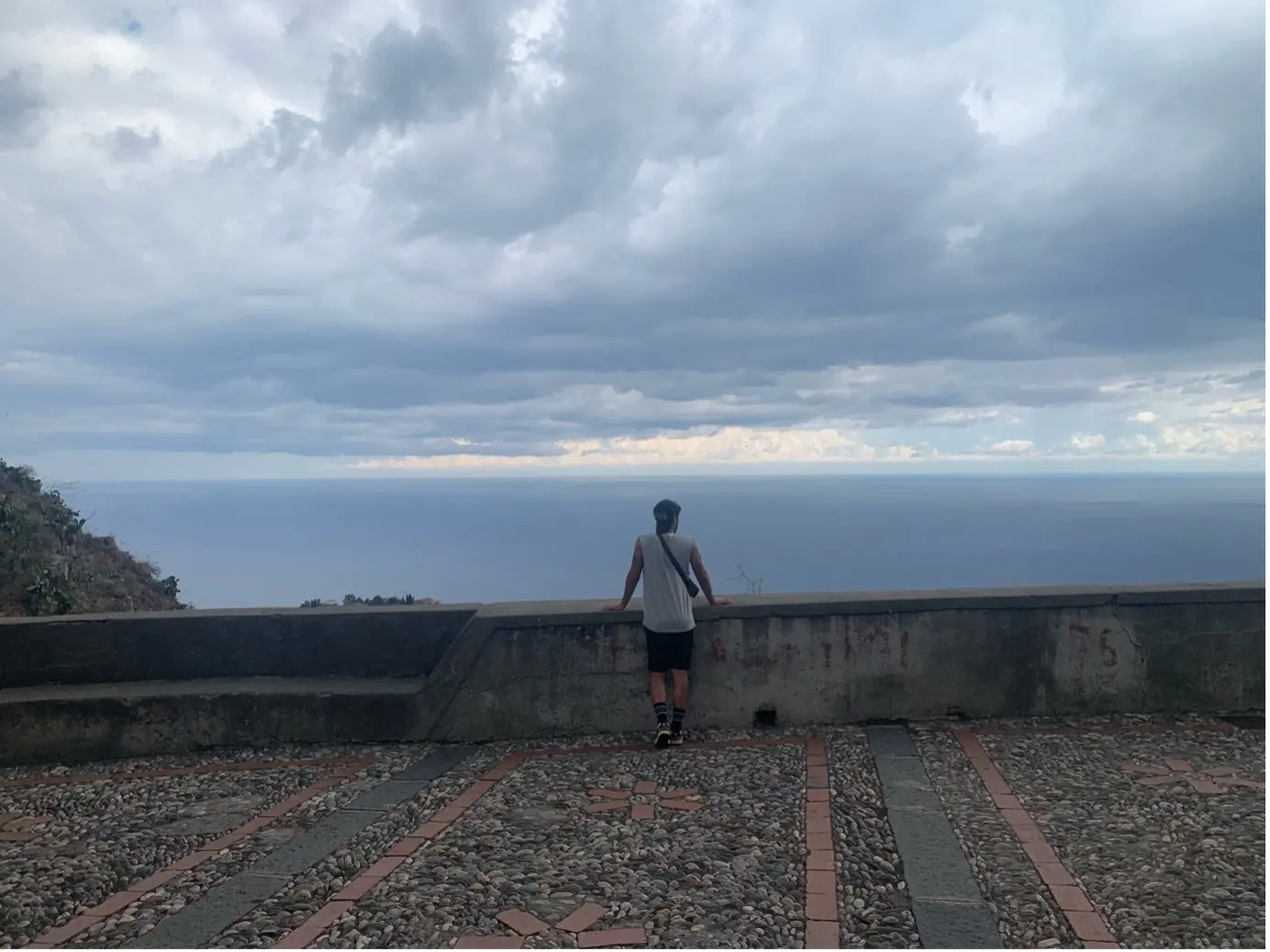 Un jeune homme contemplant la belle ville de Taormine en contrebas.