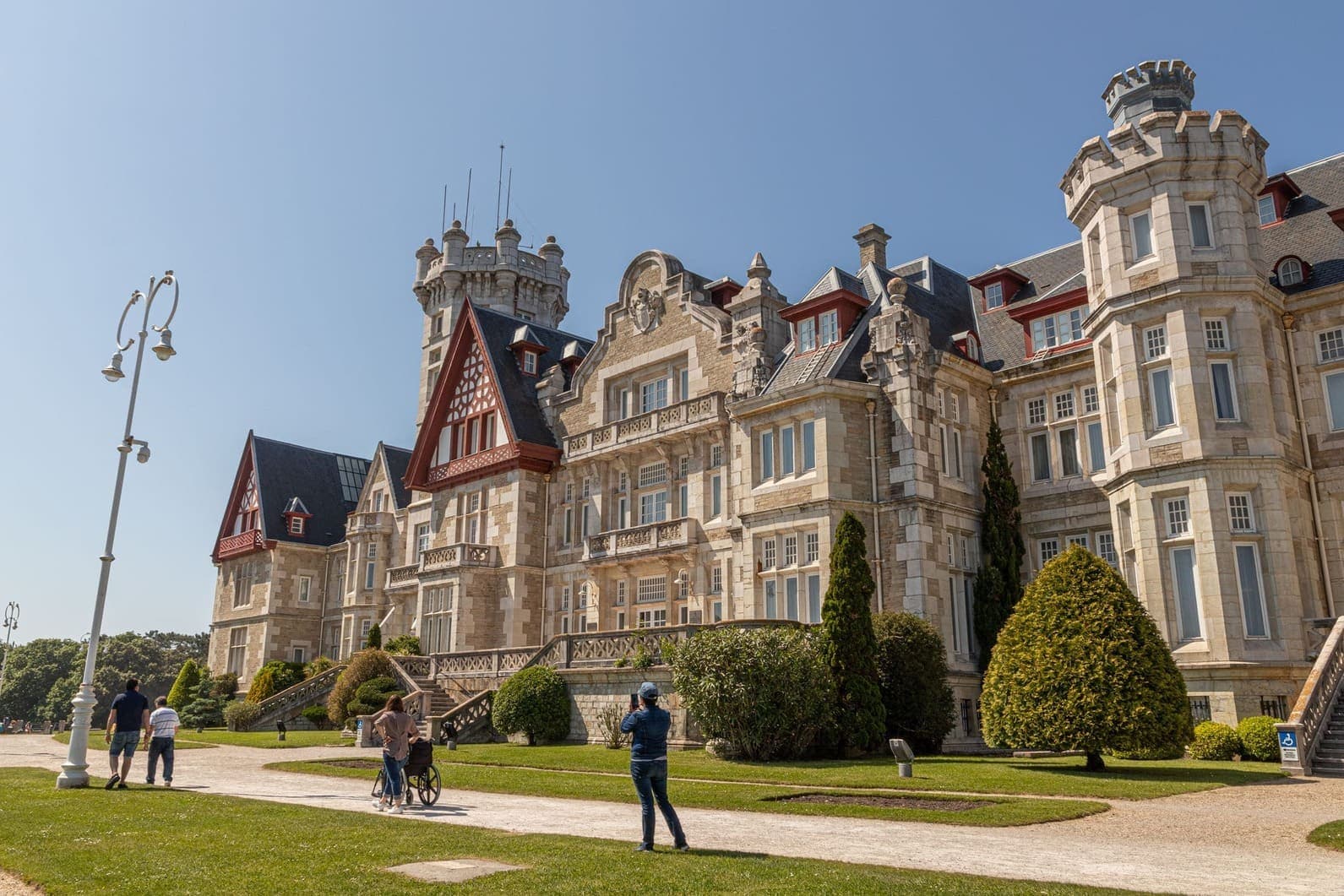 Spring view of the Palacio de la Magdalena with its grand facade, lush green lawn, and clear blue sky, once the royal summer residence of the Spanish monarchy in Santander, Spain.