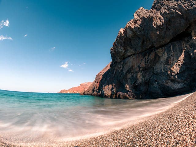 Cala rocciosa di Pantelleria con scogliera vulcanica e spiaggia di ciottoli bagnata da acqua turchese.