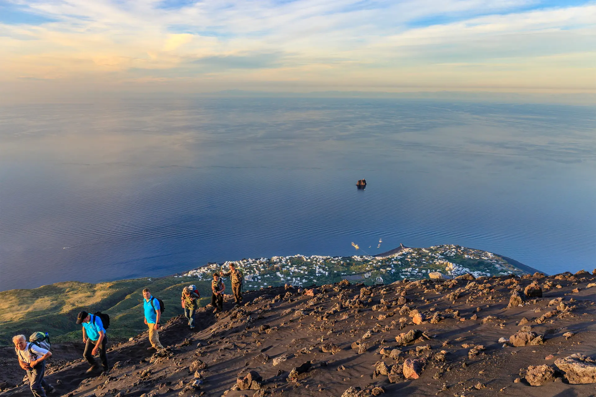 Un groupe de randonneurs sur les hauteurs du Stromboli face à l'immensité de la mer au coucher du soleil