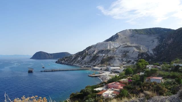 Vista panoramica della costa di Lipari con le bianche cave di pomice che scendono verso il mare turchese di Porticello, affacciate sul Mar Tirreno nelle Isole Eolie.