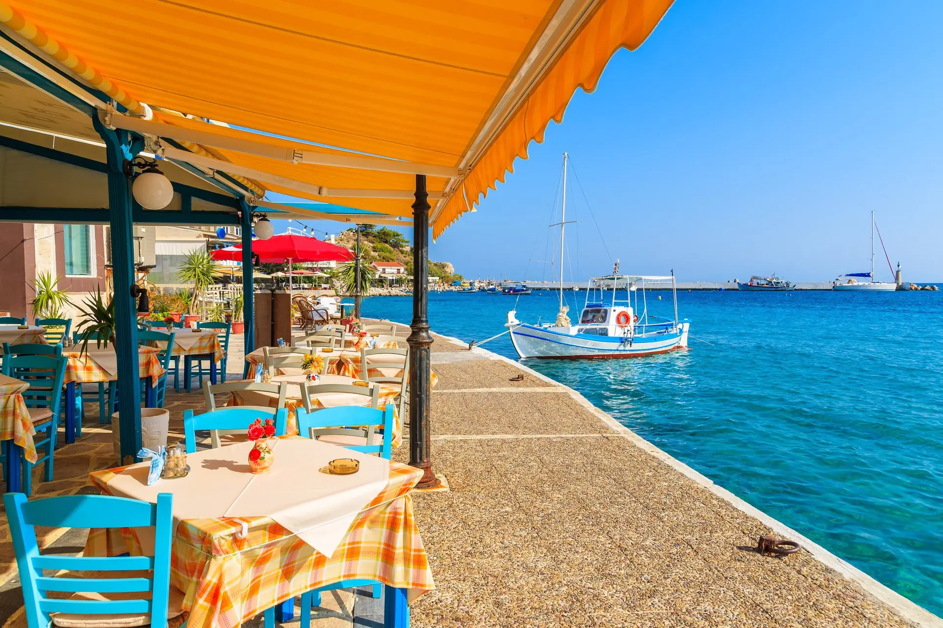 Tables with chairs in traditional Greek tavern in Kokkari town on coast of Samos island, Greece