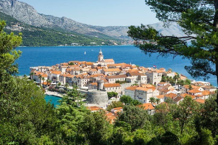 Vista dall'alto della città vecchia di Korčula, Croazia, con torri, tetti rossi e mare circostante incorniciati dal verde
