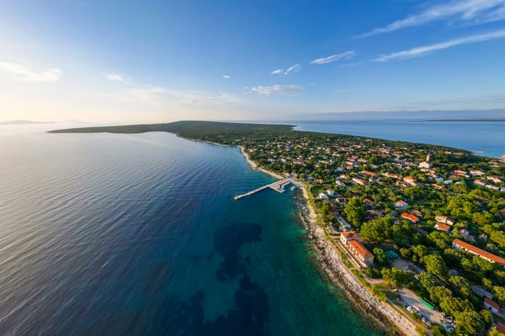 ista aerea dell'isola di Silba, Croazia, con costa frastagliata, mare cristallino e villaggio tra il verde