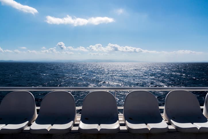 Sedute vuote sul ponte di un traghetto con vista sul mare aperto e cielo azzurro