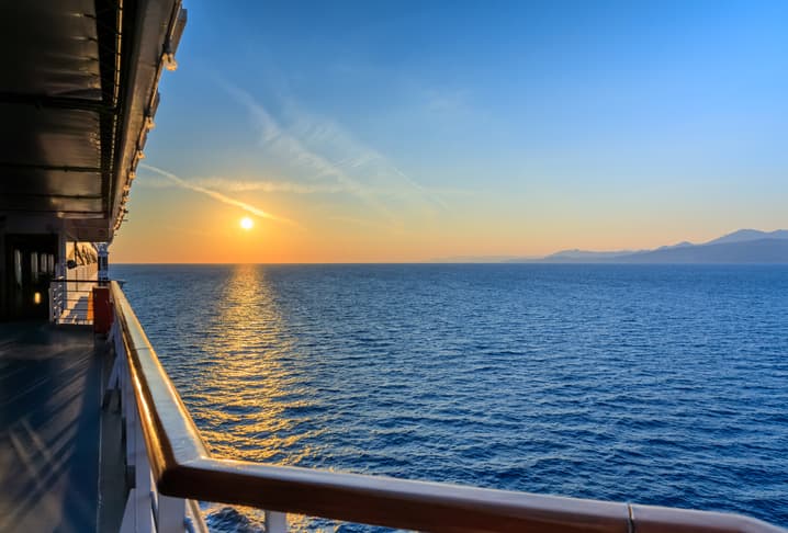 Tramonto visto dal ponte di un traghetto, con il mare calmo e la costa sullo sfondo