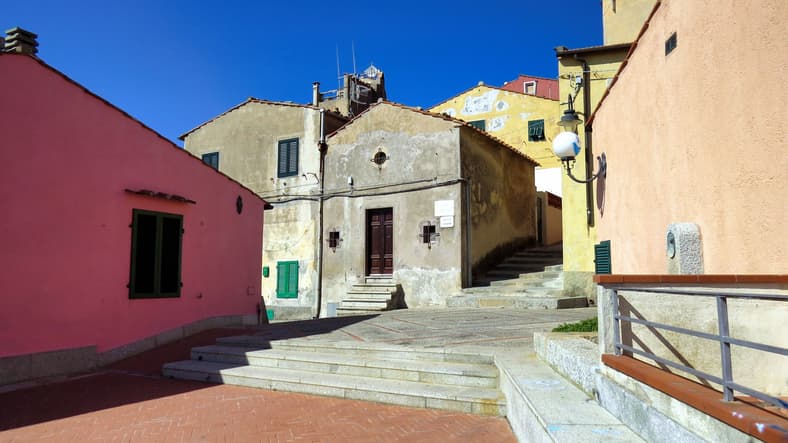 Scalinate e case colorate nel centro storico di Capoliveri, Isola d'Elba, con persiane verdi e cielo azzurro